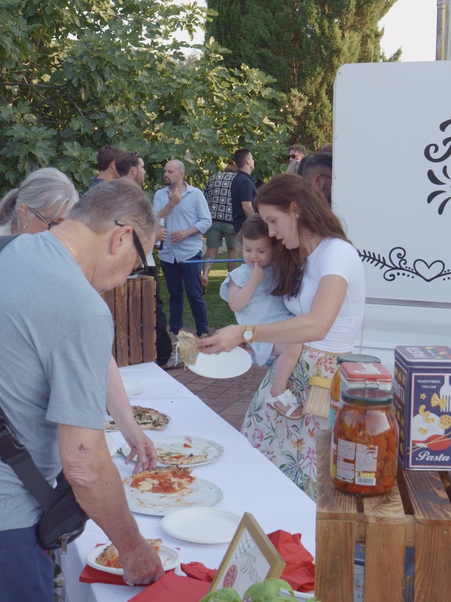 Guests serving themselves pizza at the Mamma Mia Pizza Party buffet table
