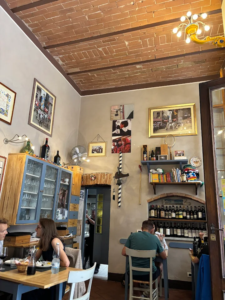 Sala interna dell'Osteria Il Carroccio a Siena con soffitto a mattoni a vista e tavoli in legno