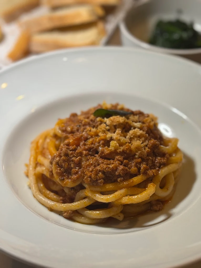 Pici al ragù con pangrattato croccante serviti all'Antica Osteria da Divo Siena