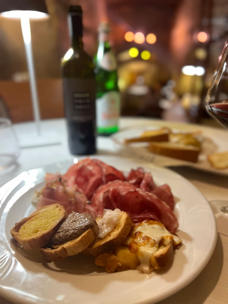 Tagliere di salumi e crostini con vino rosso all'Antica Osteria da Divo Siena