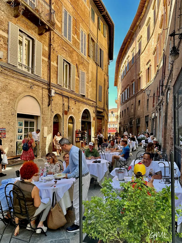 Tavoli all'aperto dell'Osteria Le Logge nel vicolo del centro storico di Siena