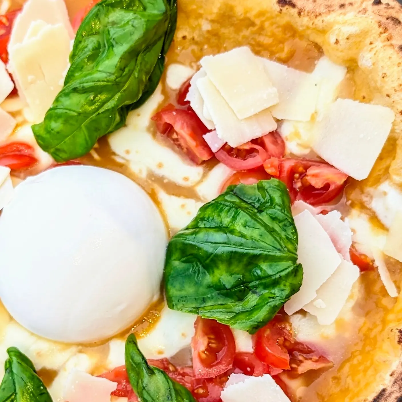 Macro di una pizza con burrata, pomodorini e basilico