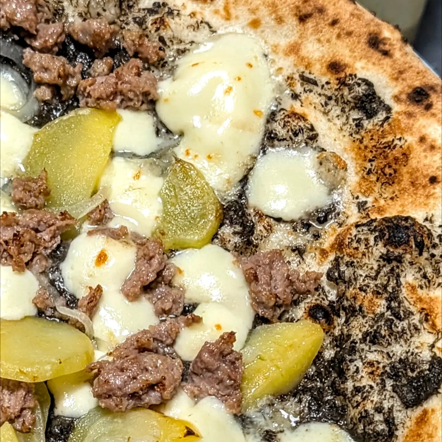 Macro di una pizza alla cenere con patate, salsiccia e mozzarella