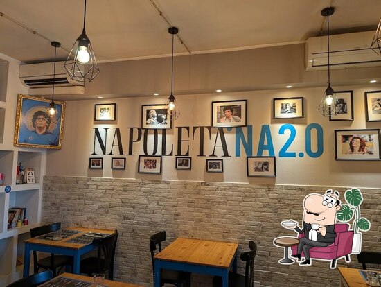 Interno della pizzeria La Napoletana 2.0 con la grande insegna NAPOLETANA 2.0