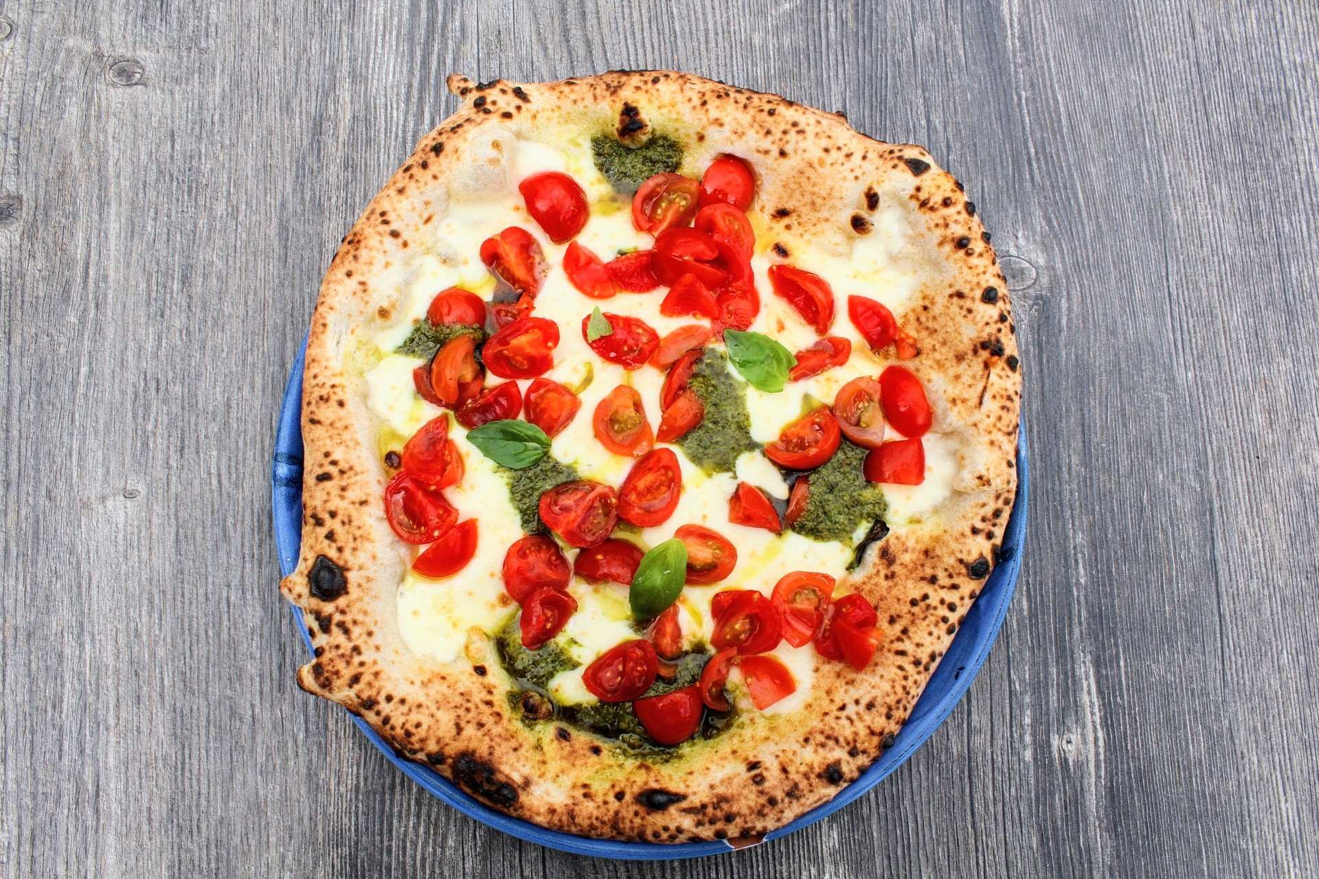Pizza con pomodorini e pesto fresco vista dall'alto