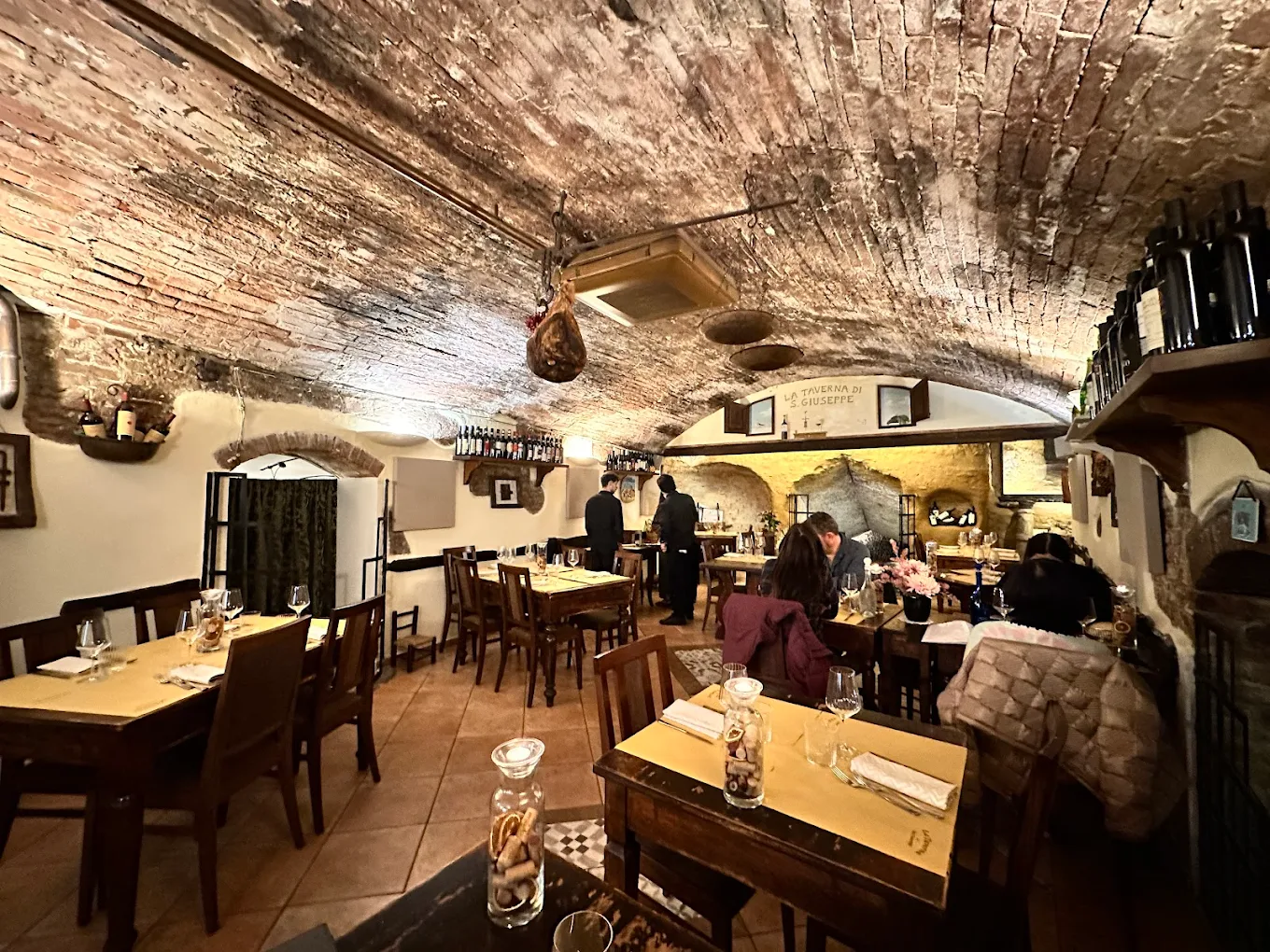Sala interna della Taverna di San Giuseppe a Siena con volte in mattoni e tavoli in legno